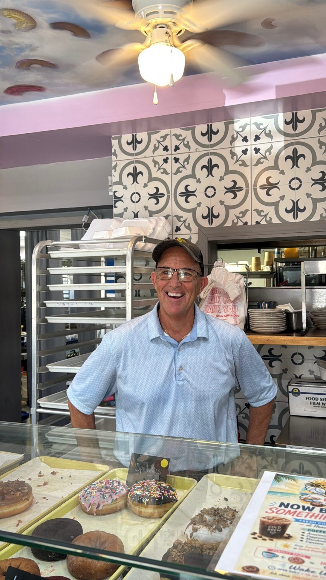 Morgan, owner of Heavenly Diner & Donuts, smiling behind the bakery case